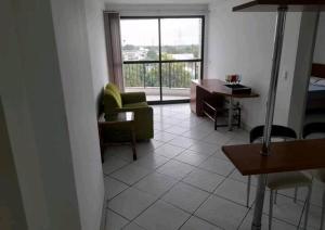 a living room with a couch and a desk and a window at Flat centro - Via Park in Campos dos Goytacazes