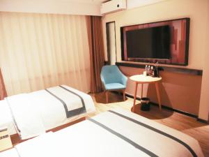 una camera con letto, TV e sedia di City Comfort Inn Shenyang Station Northern Theater General 202 Hospital a Shenyang