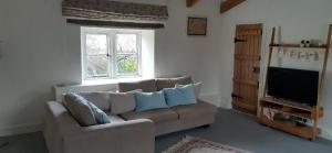 a living room with a couch and a television at The Conigre in Melksham