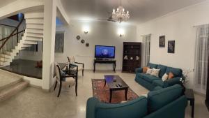 a living room with blue couches and a tv at Luxre Homes - Villa in Koramangala in Bangalore