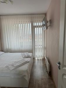 a bedroom with a bed and a large window at Апартамент Градски Парк in Dobrich