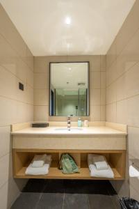 a bathroom with a sink and a mirror at City Comfort Inn Shannan Passenger Terminal in Nedong