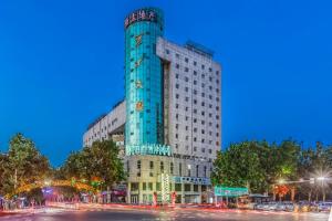 een hoog blauw gebouw in een stadsstraat 's nachts bij City Comfort Inn Handan New Century Plaza in Sucao
