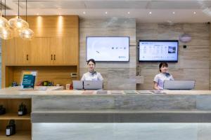 two men standing at a counter with their laptops at City Comfort Inn Handan New Century Plaza in Sucao