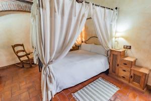 a bedroom with a canopy bed and a chair at Hotel Rural La Sinforosa in Alange