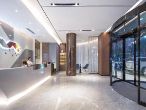 un vestíbulo de oficina con recepción y paredes de cristal en Borrman Hotel Wuzhou Teng County, en Tengcheng
