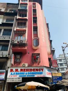 un edificio rosa alto con un cartel delante en Hotel Sagar Residency en Bombay