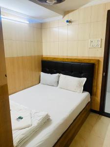 1 cama grande con sábanas blancas y almohadas en una habitación en Hotel Sagar Residency en Bombay