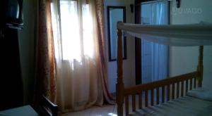 Schlafzimmer mit einem Bett und einem Fenster mit Vorhängen in der Unterkunft Trinity Guest House in Jinja