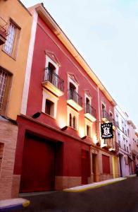 a large red building with balconies on a street at Hotel Baviera in Linares