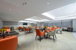 un restaurante con sillas naranjas, mesas y sillas en Echarm Hotel Wuhu Pedestrian Street High-speed Railway Station en Wuhu