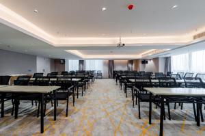 Echarm Hotel Wuhu Pedestrian Street High-speed Railway Station في Wuhu: غرفه كبيره فيها طاولات وكراسي