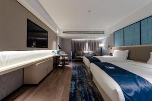 een hotelkamer met 2 bedden en een bank bij Echarm Hotel Wuhu Pedestrian Street High-speed Railway Station in Wuhu
