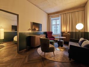 ein Hotelzimmer mit einem Sofa, Stühlen und einem Bett in der Unterkunft Straubinger Grand Hotel Bad Gastein in Bad Gastein