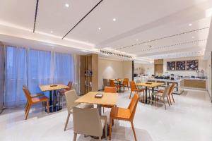 a dining room with tables and chairs and a kitchen at City Comfort Inn Yancheng Xihuan Road Wanda Plaza in Yancheng