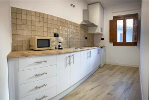 a kitchen with white cabinets and a microwave at Boutique Casa Caldereros in Córdoba