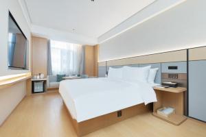 um quarto com uma grande cama branca e uma televisão em JI Hotel Weihai Liugong Island Tourism Pier em Weihai