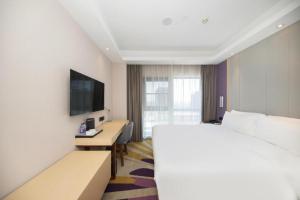 een hotelkamer met een groot bed en een televisie bij Starway Hotel Nanjing Jiaoyuan Metro Station in Jiexi