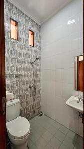 a bathroom with a toilet and a sink at Hens Guesthouse Syariah in Gadobangkong