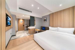 a bedroom with a large white bed and a bathroom at Starway Hotel Wenzhou Rui'an Tangxia in Xianjiayu