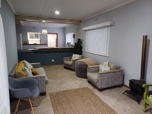 a living room with several couches and a kitchen at The Jbaynian Guesthouse in Jeffreys Bay