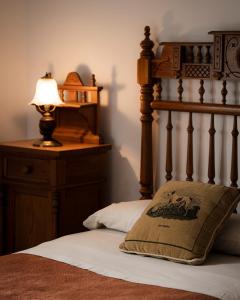 a bed with a wooden head board and a lamp at Casa Rural Dehesa de Solana in Herrera de Alcántara