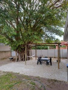 a picnic area with tables and chairs under a tree at The Jbaynian Guesthouse in Jeffreys Bay