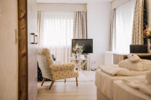 a white living room with a chair and a television at Landhotel Waldhaus in Laubach