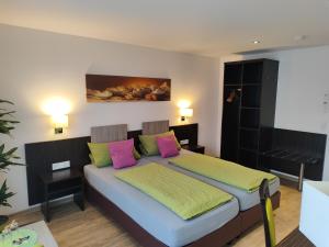 a bedroom with a bed with pink and green pillows at Hotel Stock Brotkörble in Friedrichshafen