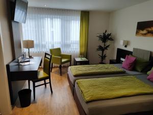 um quarto de hotel com duas camas e uma secretária em Hotel Gästehaus Stock Zimmer Brotkörble em Friedrichshafen