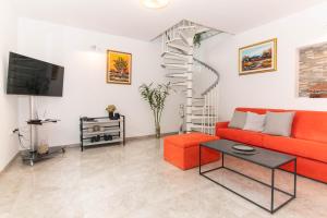 a living room with a red couch and a spiral staircase at Apartment Nonna Laura in Portorož