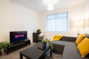 a living room with a couch and a tv at 2 Bedroom Apartment-Free Parking in Wishaw