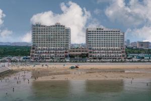 uma praia com dois edifícios altos e pessoas na praia em JI Hotel Yantai Development Zone Housha Plaza em Zhuji