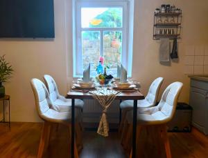 a dining room table with white chairs and a window at Bergling Apartment im Zentrum • Netflix • Festungsblick • Obst und Wein • in Königstein an der Elbe