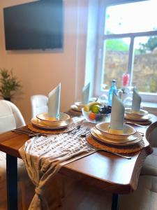 een houten tafel met borden en borden erop bij Bergling Apartment im Zentrum • Netflix • Festungsblick • Obst und Wein • in Königstein an der Elbe