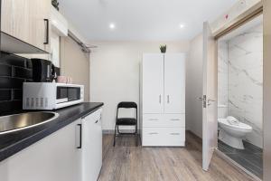 a white kitchen with a sink and a microwave at Charming Serviced Ensuite Modern Studio - Sleeps 2 - Near Wembley Stadium - Good Transport Link to Central London - Harrow HA3 in Hatch End