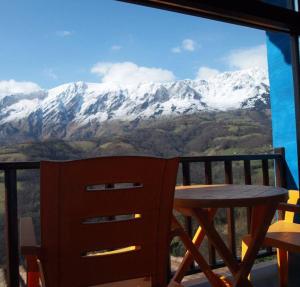 a table and chair on a balcony with a snow covered mountain at LA ALDEA SOÑADA in Oviedo