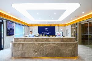 a woman standing at a counter in a lobby at Starway Hotel Nanchang West Lake Wanda Plaza in Taohua