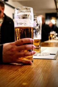 una persona sosteniendo un vaso de cerveza en una mesa en George Hotel & Granary, en Frome