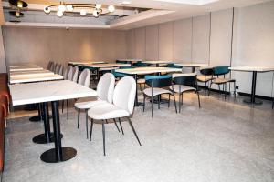 Cette grande chambre dispose de tables et de chaises. dans l'établissement NIHAO Hotel Hailar Zhongyangqiao Ancient City, à Hulunbuir