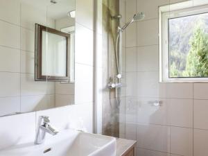 ein Bad mit einem Waschbecken und einer Dusche mit einem Spiegel in der Unterkunft Apartment with Baltic Sea view in Sautens