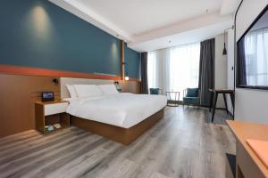 a hotel room with a large bed and a desk at NIHAO Hotel Linyi Jiefang East Road Financial Building in Linyi
