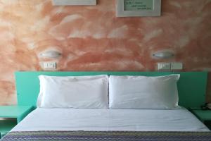 uma cama com duas almofadas brancas num quarto em Hotel Crosal em Rimini