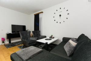 salon z kanapą i zegarem na ścianie w obiekcie GOLD Apartman w mieście Sanski most