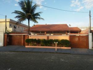 une maison avec une clôture et un palmier dans l'établissement Casa Itanhaém, à Itanhaém