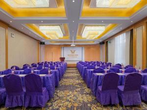 uma sala de conferências com cadeiras roxas e um ecrã em Vienna Hotel Qinghai Xining Wanda Plaza em Xining