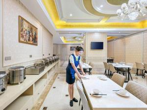Kobieta stojąca przy stole w restauracji w obiekcie Vienna Hotel Shanghai Songjiang Xiaokunshan w mieście Chengxi