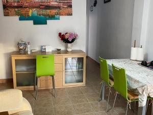 uma sala de jantar com uma mesa e cadeiras verdes em Cosy apartment with shared balcony em Sevilha