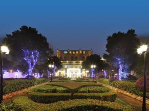 un gran edificio con luces frente a un jardín en Vienna Hotel Shanghai Hongqiao Hub National Exhibition Center Huqingping Road en Shanghái