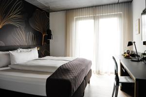 a bedroom with a bed and a desk and a window at Hotel BalthazarS in Seligenstadt